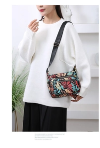 Detail view of floral nylon crossbody bag with multi-pocket design and adjustable strap