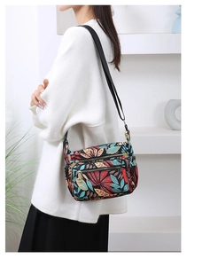 Detail view of the tropical leaf print pattern on a multi-zip nylon crossbody bag for women