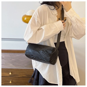 Lifestyle shot of black cylinder shoulder bag with unique wrinkled texture on a model