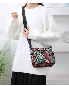 Floral print nylon crossbody bag detail showing multi-layer zipper and adjustable strap