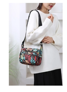 Detail of a floral nylon crossbody bag with multi-zipper pockets and colorful maple pattern