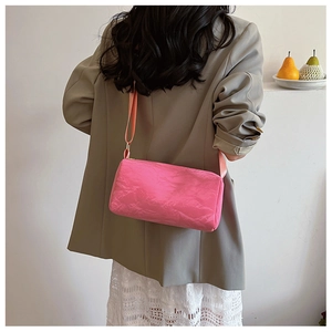 Detail view of pink cylinder shoulder bag with unique paper-like wrinkled texture and strap