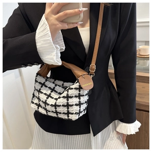Detail of classic black and white tweed crossbody bag with brown leather twisted handle