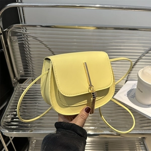 Minimalist light yellow crossbody bag with gold metal trim and tassel accent