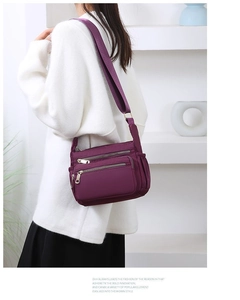 Detail view of purple nylon crossbody bag with multi-zipper pockets and wide shoulder strap