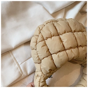 Close-up of quilted beige cloud bag showing detailed square stitching and nylon texture