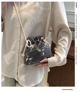 Détail du sac seau gris à cordon avec broderie florale rose et bandoulière en corde de coton