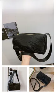 Detail showing the black cylinder shoulder bag with textured fabric and gold zipper