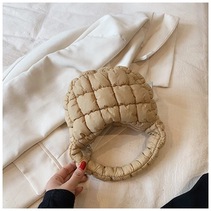 Detail of light beige quilted puffer handbag with checkered texture and zip closure