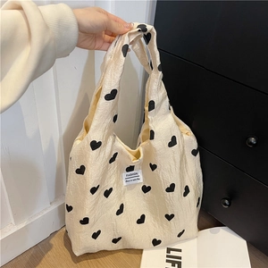 Chic cream pleated tote bag with black heart patterns and fashion label handle view