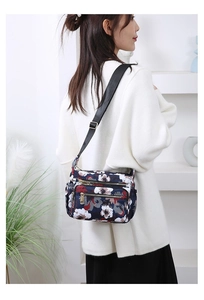 Floral crossbody bag detail showing multi-pocket design on adjustable shoulder strap