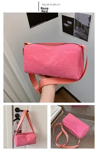 Detail of rose red cylinder shoulder bag with glossy pleated texture and wide strap