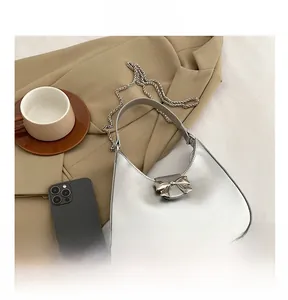 Detailed view of silver bow metal buckle and metallic leather texture on handbag