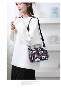 Detail view of floral nylon crossbody bag with adjustable wide strap and zip pockets