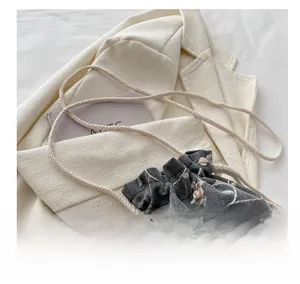 Détail de la broderie florale sur sac seau gris à cordon avec bandoulière tissée