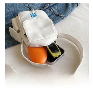 Innenansicht einer kompakten weißen Umhängetasche aus Nylon mit Sonnenbrille und Box