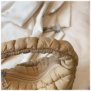 Detailed macro view of the silver metal zipper and quilted fabric on the beige cloud bag