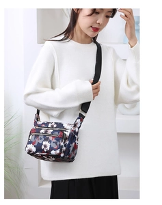 Floral nylon crossbody bag with multi-layer zipper pockets worn by a model