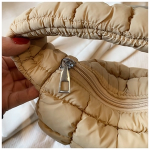 Detail of beige quilted cloud bag showing soft padded fabric and silver square zipper