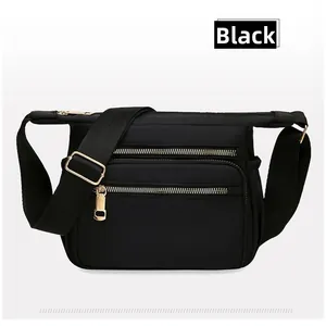 Detail of black nylon crossbody bag with gold metal zippers and adjustable wide strap