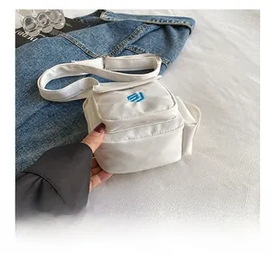 Detail der weißen Nylon-Umhängetasche mit blauem Logo und verstellbarem Schultergurt