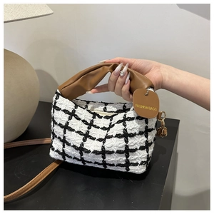 Detail of the black and white plaid tote bag featuring a pleated brown leather handle