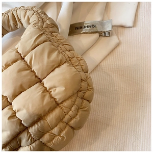 Close-up detail of khaki quilted puffer bag showing soft wrinkled texture and stitching