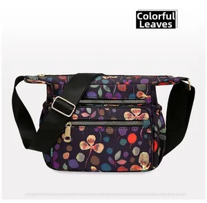 Close-up of lightweight floral nylon crossbody bag with three zipper pockets and colorful leaf print