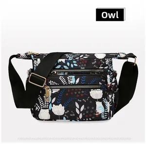 Close-up of black nylon floral owl bag featuring golden zippers and multi-layer pockets