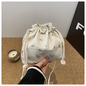 Gros plan sur la broderie de roses roses d'un sac seau en toile écrue à cordon