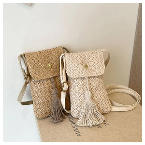 Détail du sac à bandoulière en paille pour téléphone avec pompon et boucle dorée