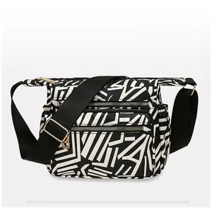 Detail view of the multi-pocket nylon crossbody bag with abstract stripe pattern and zippers