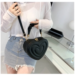 Detail of a black heart-shaped handbag with quilted texture and gold zipper hardware