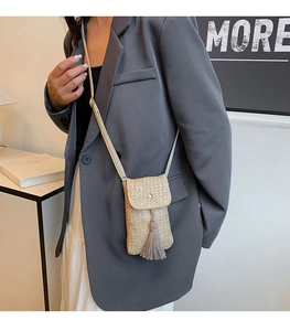Gros plan du sac de téléphone tissé beige avec pompon à franges sur un mannequin
