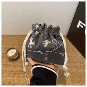 Détail de la broderie florale sur sac à cordon en filet gris avec cordons en coton naturel