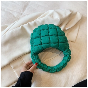 Detail view of emerald green quilted puffer bag featuring a glossy nylon texture and zip closure