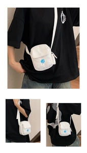 Detailansichten einer weißen Canvas-Umhängetasche mit blauem Logo und verstellbarem Gurt