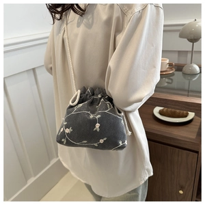Détail du sac seau gris à cordon avec broderie florale et bandoulière en coton doux