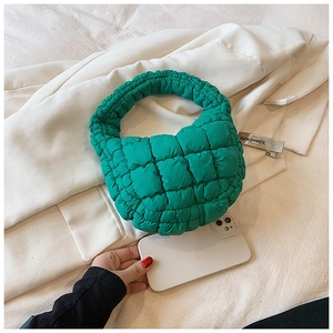 Detail of a vibrant green quilted cloud bag on a beige blazer with a phone for size