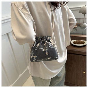 Détail d'un petit sac seau gris foncé à cordon avec broderie florale rose élégante