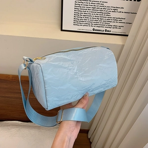 Minimalist light blue cylinder shoulder bag with textured fabric and wide strap