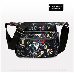 Close-up of black nylon crossbody bag featuring vibrant floral prints and golden zippers