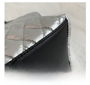 Détail des coutures précises sur un sac fourre-tout argenté matelassé avec base noire