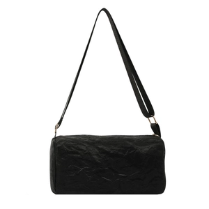 Minimalist black cylinder shoulder bag with textured pleats and golden metal hardware