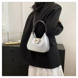 Detail of silver half-moon bag with metallic bow buckle and slim chain strap