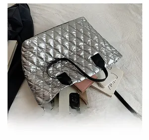 Détail d'un grand sac cabas argenté matelassé contenant une tablette et un téléphone