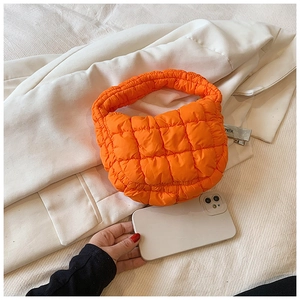 Detailed view of an orange quilted cloud bag showing soft padded fabric and texture