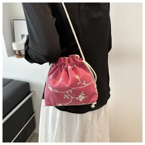 Détail du sac seau en velours rose avec broderies florales et fermeture par cordon