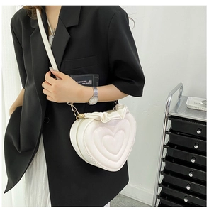Detail of white heart-shaped crossbody bag featuring ruffled trim and layered stitching