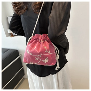 Détail du sac seau rose à cordon avec broderie florale et bandoulière en corde de coton